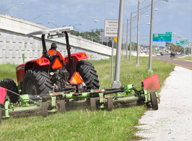 Tractor with a mowing deck cutting a highway roadside verge